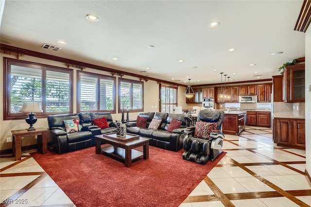 living area featuring recessed lighting, visible vents, baseboards, and crown molding