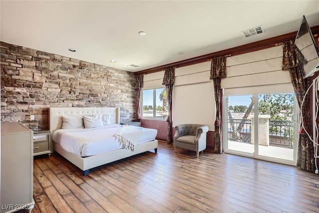 bedroom with access to exterior, visible vents, and hardwood / wood-style flooring