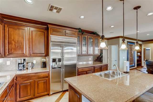 kitchen with brown cabinetry, visible vents, recessed lighting, a sink, and built in refrigerator