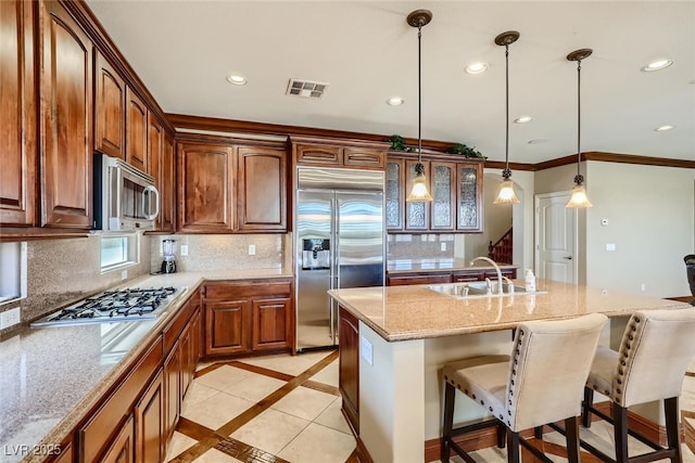 kitchen with a breakfast bar area, visible vents, a sink, decorative backsplash, and stainless steel appliances