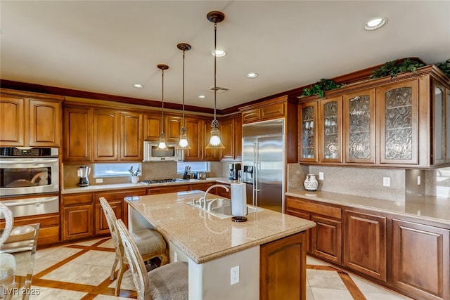 kitchen with brown cabinetry, a sink, decorative backsplash, stainless steel appliances, and a warming drawer