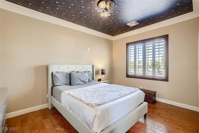 bedroom featuring crown molding, baseboards, visible vents, and wood-type flooring