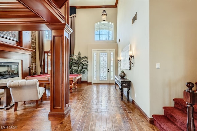 entrance foyer with visible vents, stairway, a glass covered fireplace, and hardwood / wood-style floors