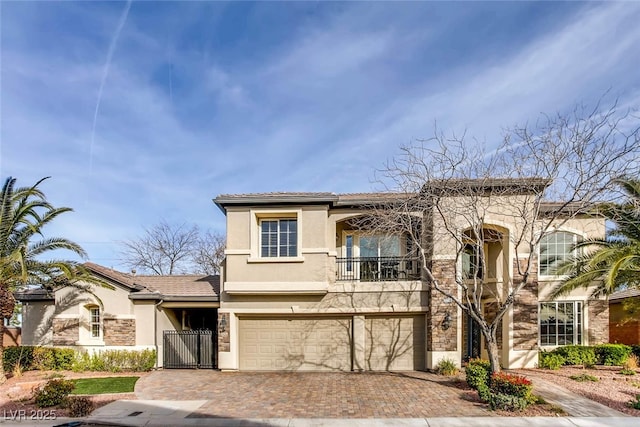 mediterranean / spanish-style home with stucco siding, decorative driveway, a garage, a balcony, and a gate