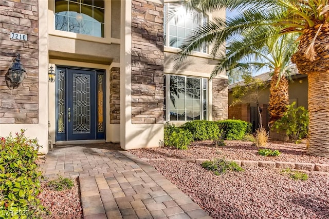 property entrance featuring stucco siding and stone siding