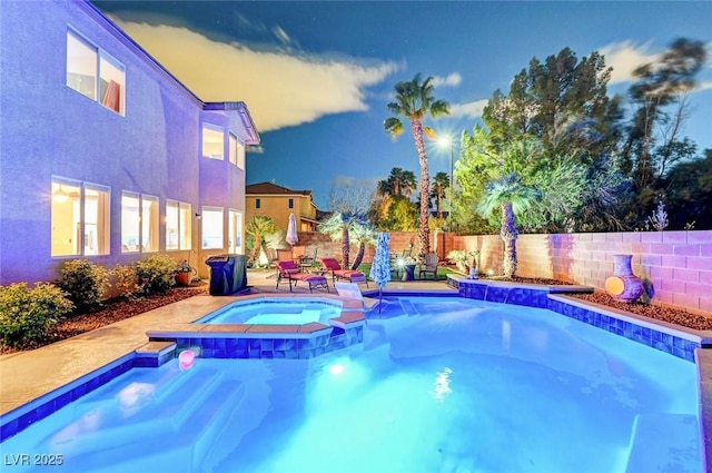 view of swimming pool with a patio area, a pool with connected hot tub, and fence