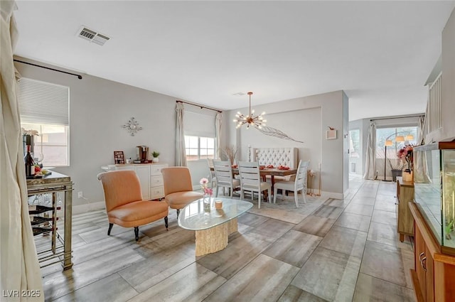 living area with a notable chandelier, visible vents, light wood-type flooring, and baseboards