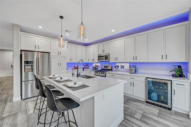 kitchen featuring visible vents, beverage cooler, light countertops, stainless steel appliances, and a sink