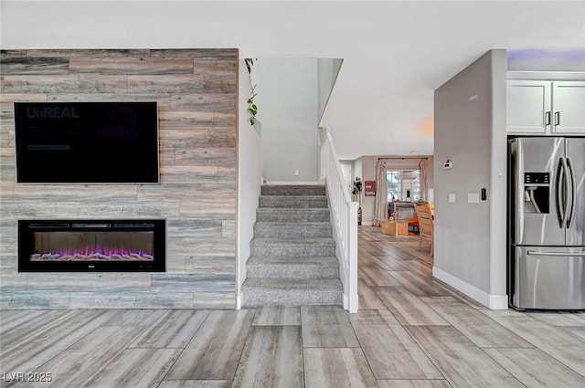 stairway featuring a glass covered fireplace, baseboards, and wood tiled floor