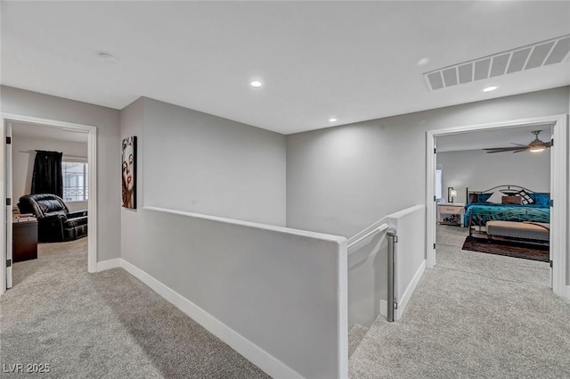 corridor featuring visible vents, baseboards, an upstairs landing, carpet flooring, and recessed lighting