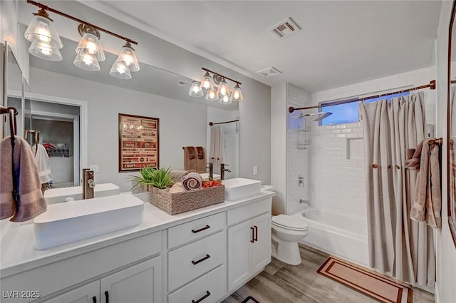 bathroom featuring double vanity, wood finished floors, visible vents, and a sink