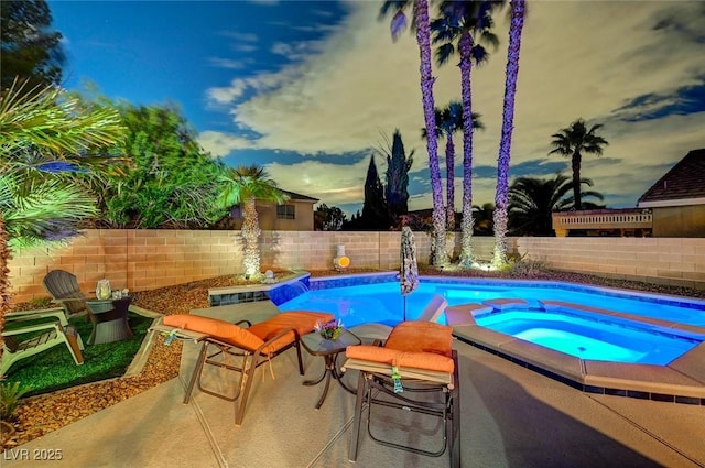 view of swimming pool with a fenced backyard and a pool with connected hot tub