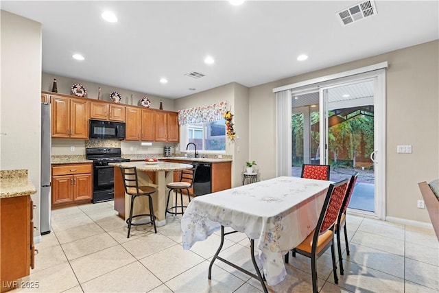 kitchen featuring a sink, visible vents, black appliances, and a center island