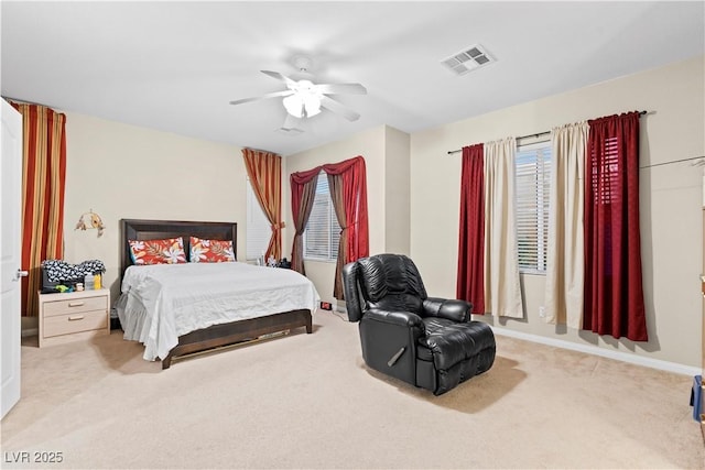 bedroom with visible vents, light colored carpet, baseboards, and ceiling fan