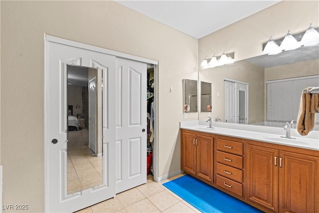 bathroom with a sink, a spacious closet, double vanity, and tile patterned floors