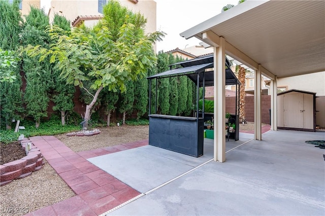 view of patio / terrace featuring a gazebo, an outbuilding, a storage unit, and fence