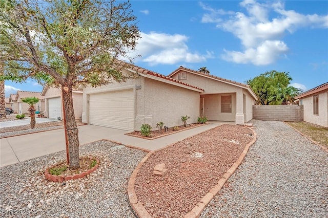 view of front of property featuring fence, a tiled roof, concrete driveway, stucco siding, and an attached garage