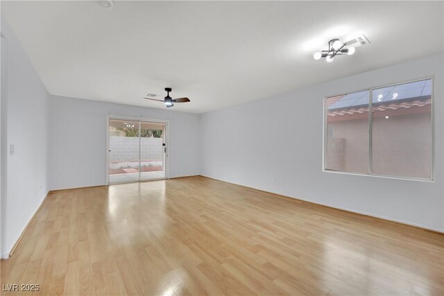 spare room featuring ceiling fan with notable chandelier and light wood finished floors