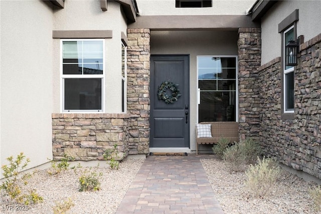 view of exterior entry featuring stucco siding and stone siding