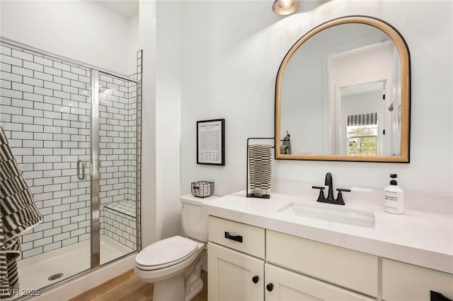 bathroom featuring vanity, a shower stall, toilet, and wood finished floors