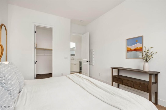 bedroom featuring baseboards, wine cooler, and a walk in closet