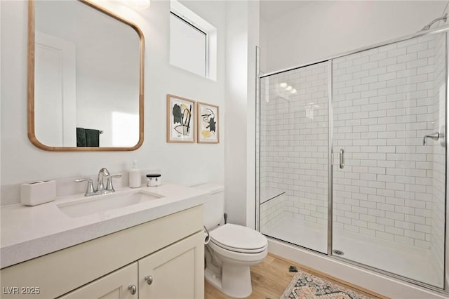 full bathroom featuring vanity, toilet, wood finished floors, and a stall shower