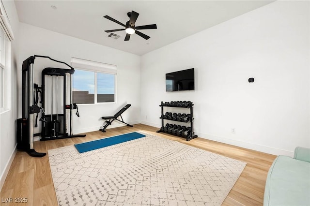 workout area featuring baseboards, visible vents, light wood finished floors, and ceiling fan