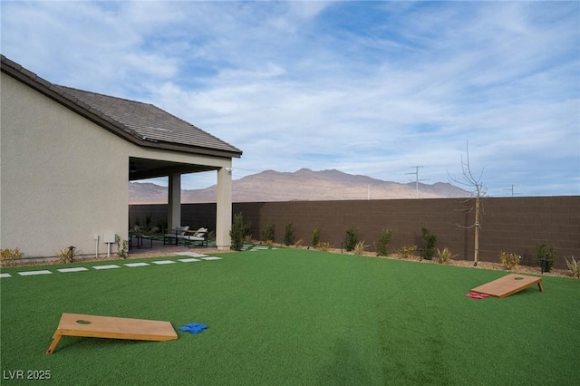 view of yard featuring a patio, a fenced backyard, and a mountain view