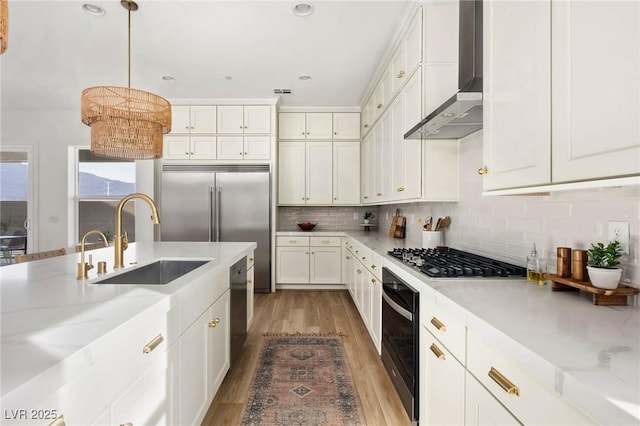 kitchen featuring stainless steel gas cooktop, a sink, oven, wall chimney range hood, and tasteful backsplash