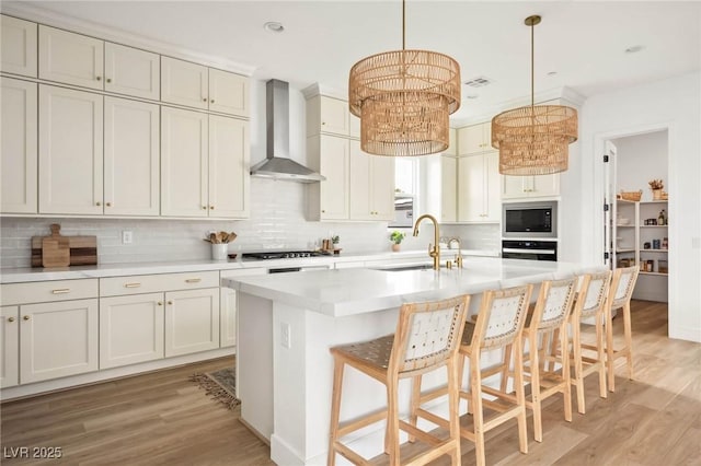 kitchen with oven, wall chimney range hood, built in microwave, gas cooktop, and a sink