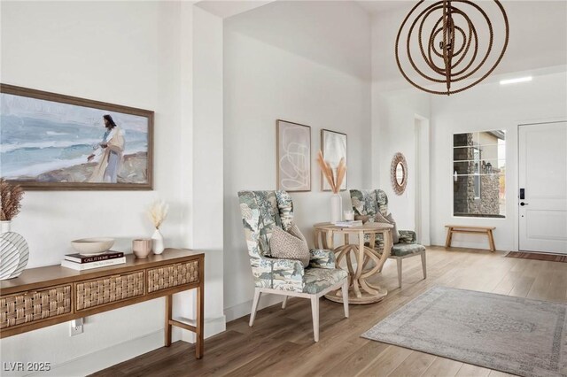 foyer entrance featuring a chandelier, baseboards, a high ceiling, and wood finished floors