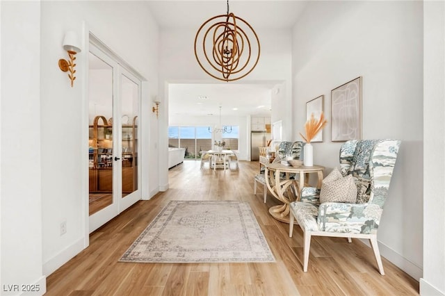 corridor featuring french doors, baseboards, a notable chandelier, and wood finished floors