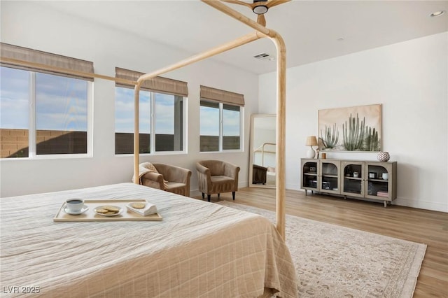 bedroom with visible vents, baseboards, and wood finished floors