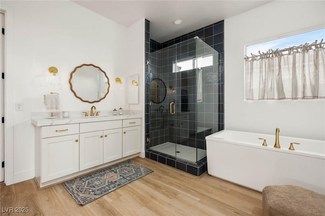 full bathroom with a stall shower, a soaking tub, wood finished floors, and vanity