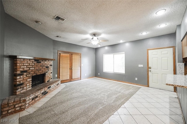 living area with visible vents, a brick fireplace, baseboards, ceiling fan, and light carpet