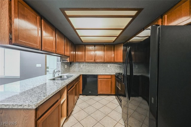 kitchen with light tile patterned flooring, a sink, decorative backsplash, black appliances, and brown cabinets