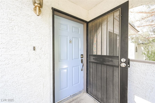 doorway to property featuring stucco siding