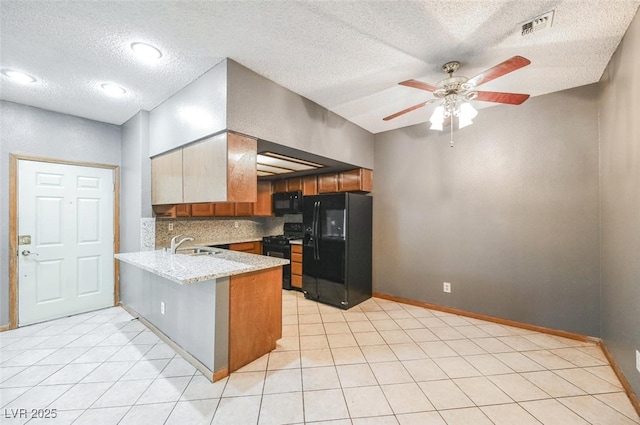 kitchen with brown cabinetry, visible vents, a peninsula, a sink, and black appliances