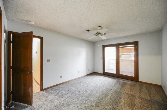 carpeted spare room featuring a textured ceiling, baseboards, visible vents, and ceiling fan