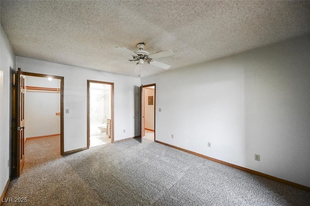 unfurnished bedroom featuring a spacious closet, connected bathroom, baseboards, carpet floors, and a textured ceiling