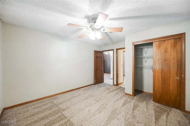 unfurnished bedroom with a closet, a textured ceiling, baseboards, and carpet floors