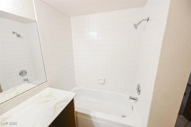 full bath with bathtub / shower combination, vanity, and a textured wall