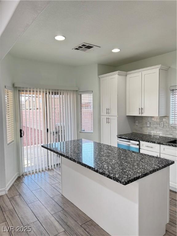 kitchen with visible vents, dishwasher, white cabinets, and decorative backsplash