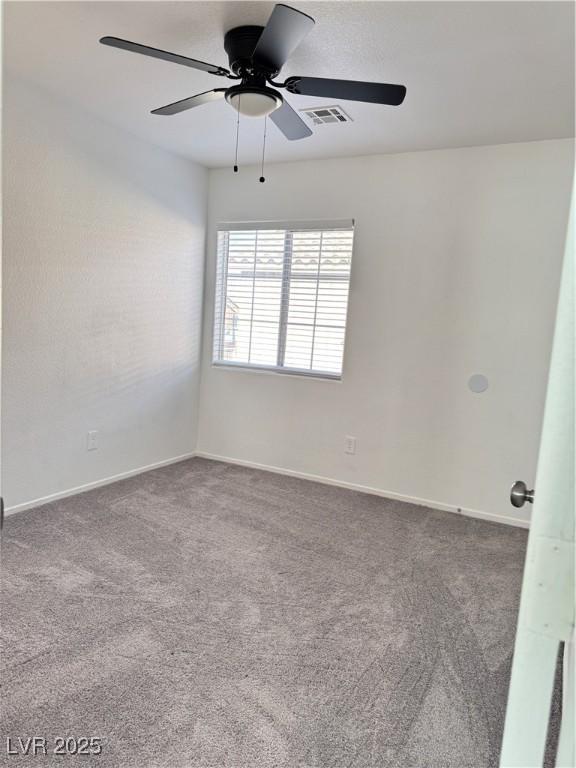 carpeted empty room with visible vents, baseboards, and a ceiling fan