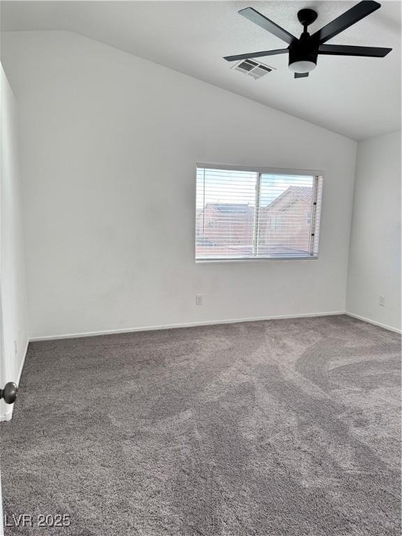 empty room featuring lofted ceiling, a ceiling fan, visible vents, and carpet floors