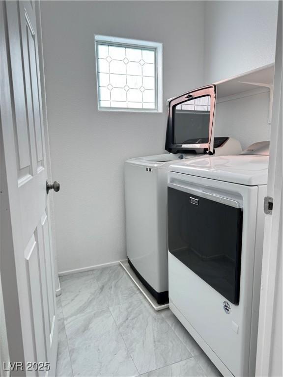 laundry room with baseboards, marble finish floor, laundry area, and washing machine and clothes dryer