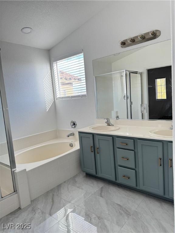 bathroom featuring a garden tub, double vanity, a stall shower, and a sink