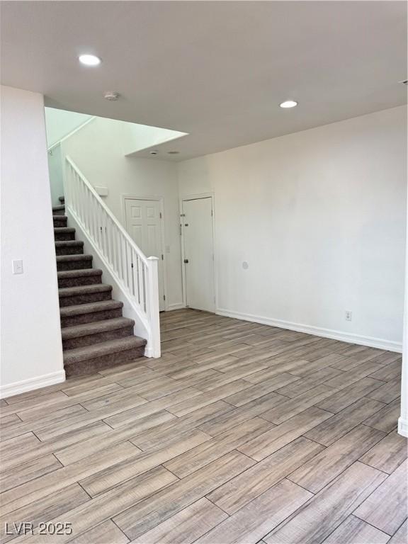 unfurnished room with recessed lighting, stairs, baseboards, and wood finished floors