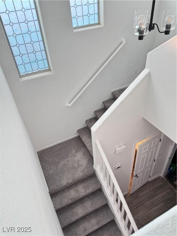 stairs featuring wood finished floors and a chandelier