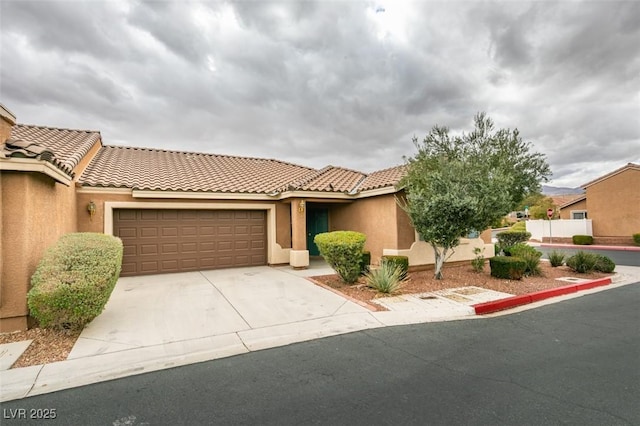 view of front of property with stucco siding, driveway, an attached garage, and a tile roof